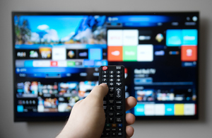 A photo of a person pointing a television remote towards a smart TV